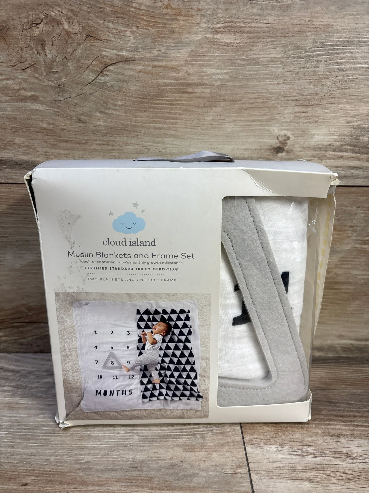Front view of Cloud Island muslin blanket and felt frame set showing white blanket and gray felt frame in original box on wood surface
