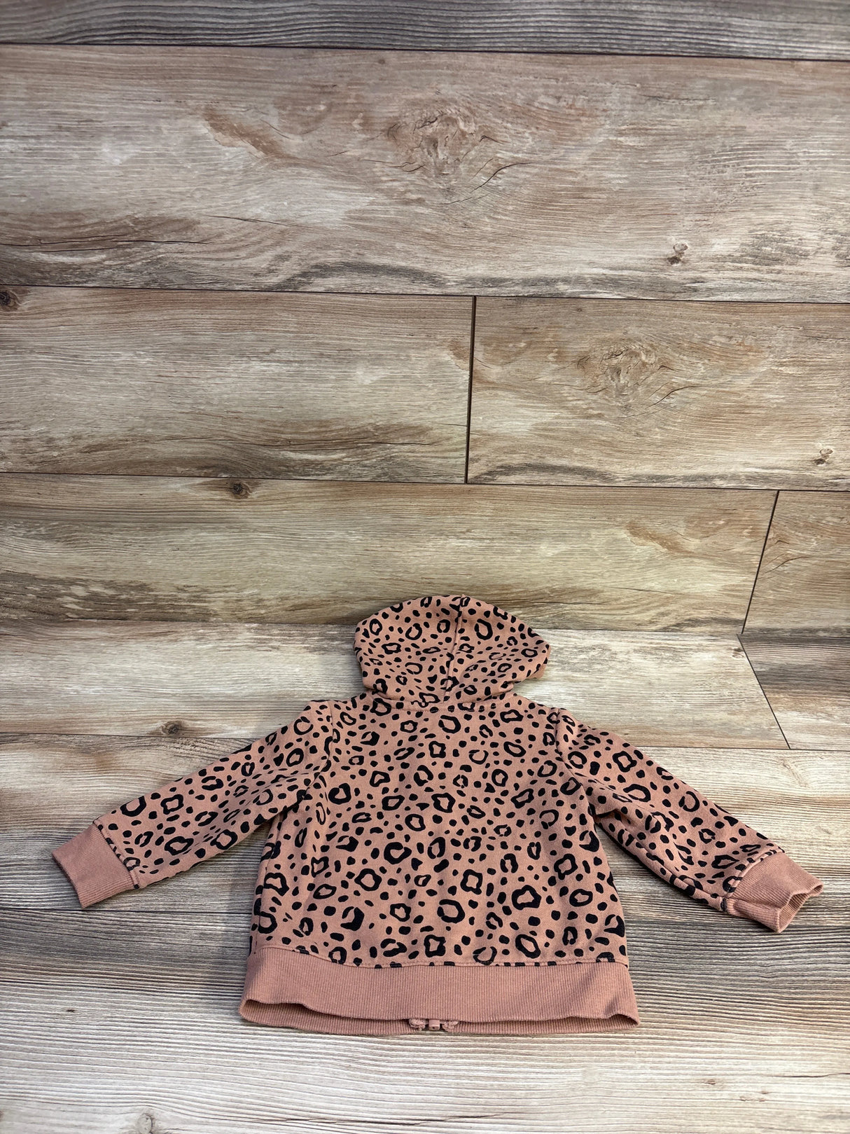 Back view of Cat & Jack toddler hooded jacket showcasing brown leopard print pattern laid flat on wooden background