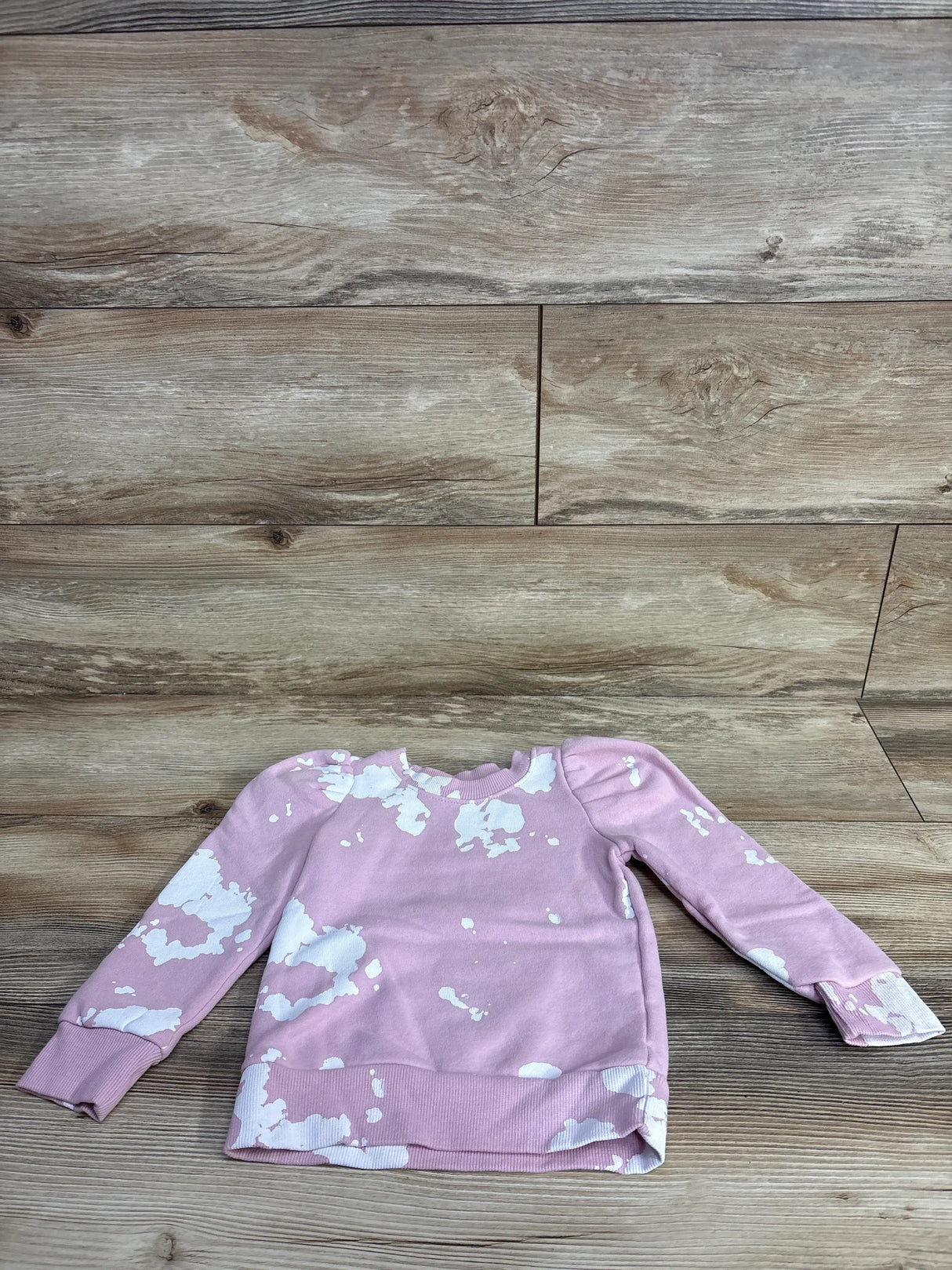 Pink long sleeve girls sweatshirt with white splatter print on wood background