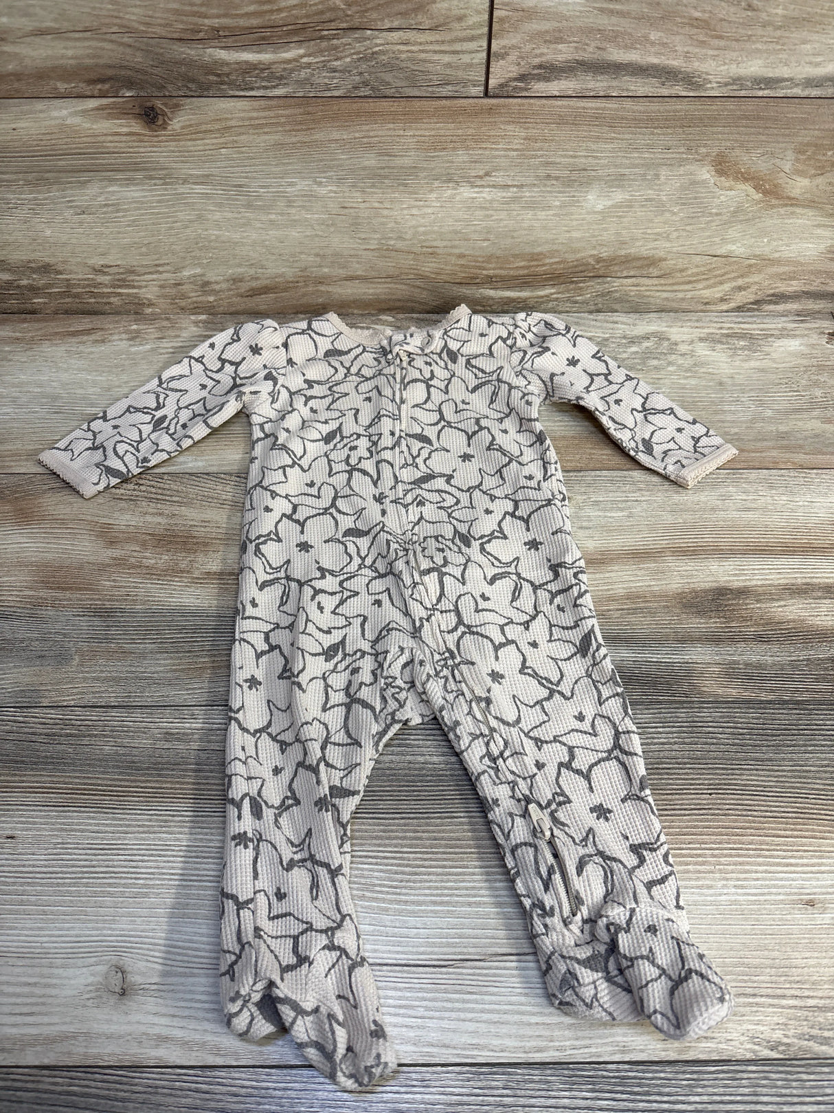 Floral long sleeve baby sleeper with zipper on wood background