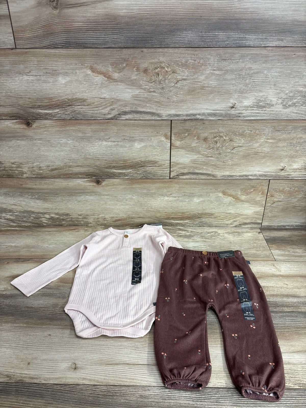 Top view of Modern Moments 2pc ribbed bodysuit and pants set in pink, with long sleeves and floral-print pants on wood floor