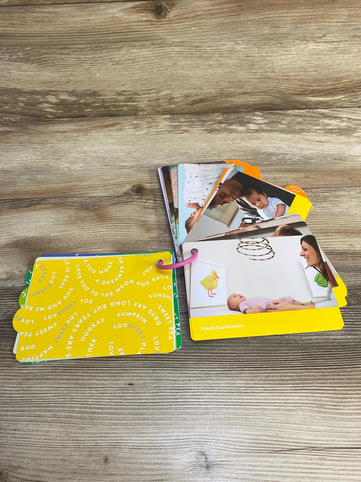 Baby activity flash cards with photos and bright yellow covers on wooden table