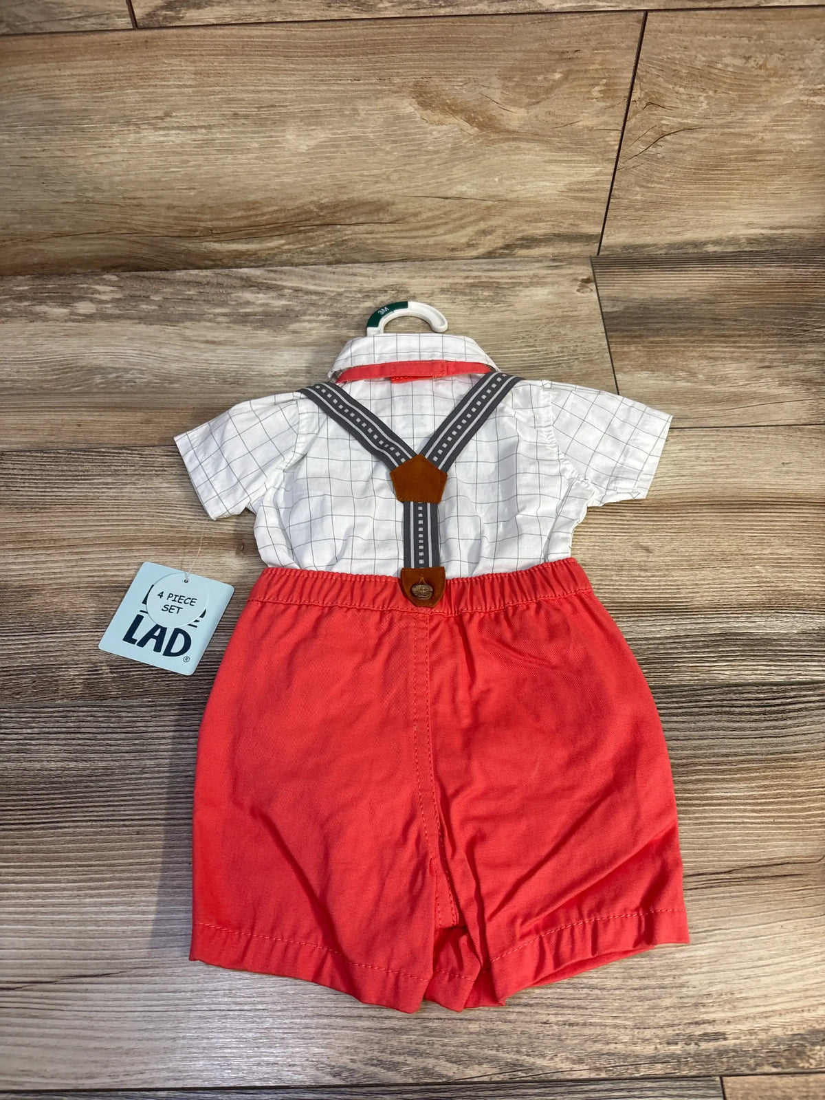 Front view of Little Lad 4-piece suspender set with white button-up bodysuit, red shorts, suspenders, and bowtie