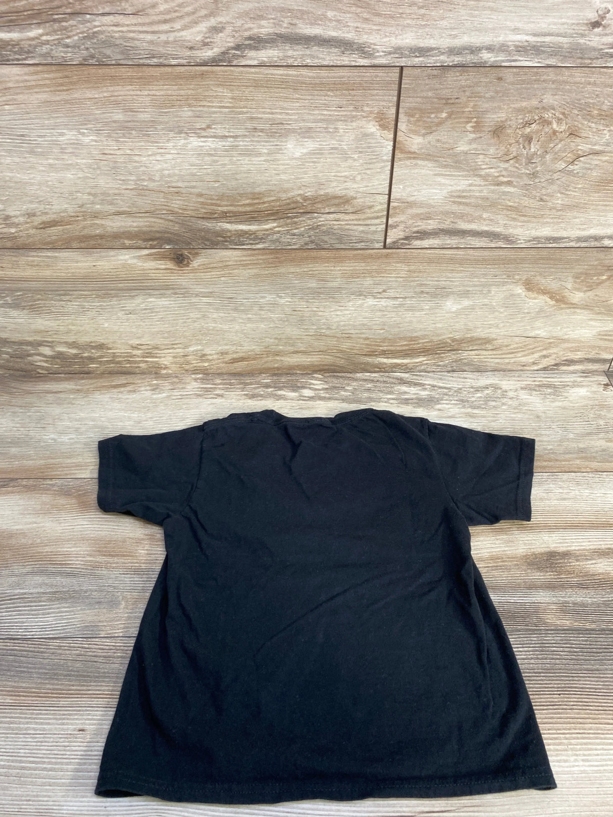Black kids t-shirt laid flat on wood floor, kids clothing resale