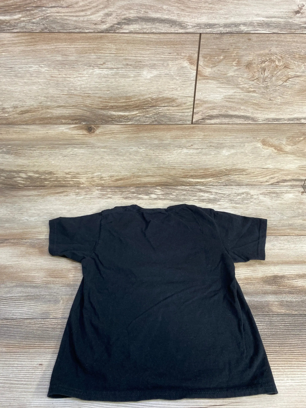 Back view of black Crush Breast Cancer ghost kids t-shirt size 4T showing plain back on wood floor