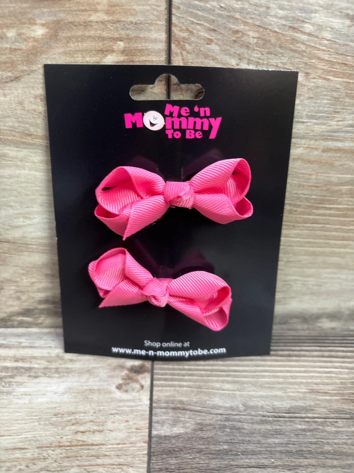 Two bright pink grosgrain hair bows on a Me n Mommy To Be branded black display card.