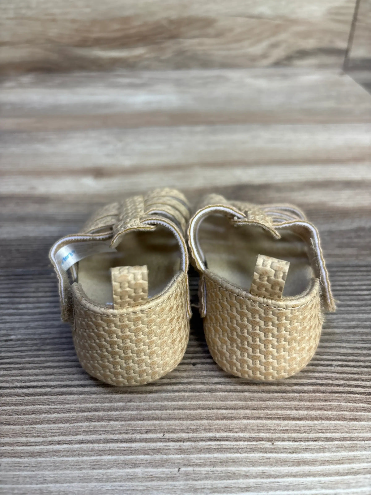 Rear view of Carter’s Strappy Sandals Beige sz 2/3c showcasing woven brown straps on a wood-grain background