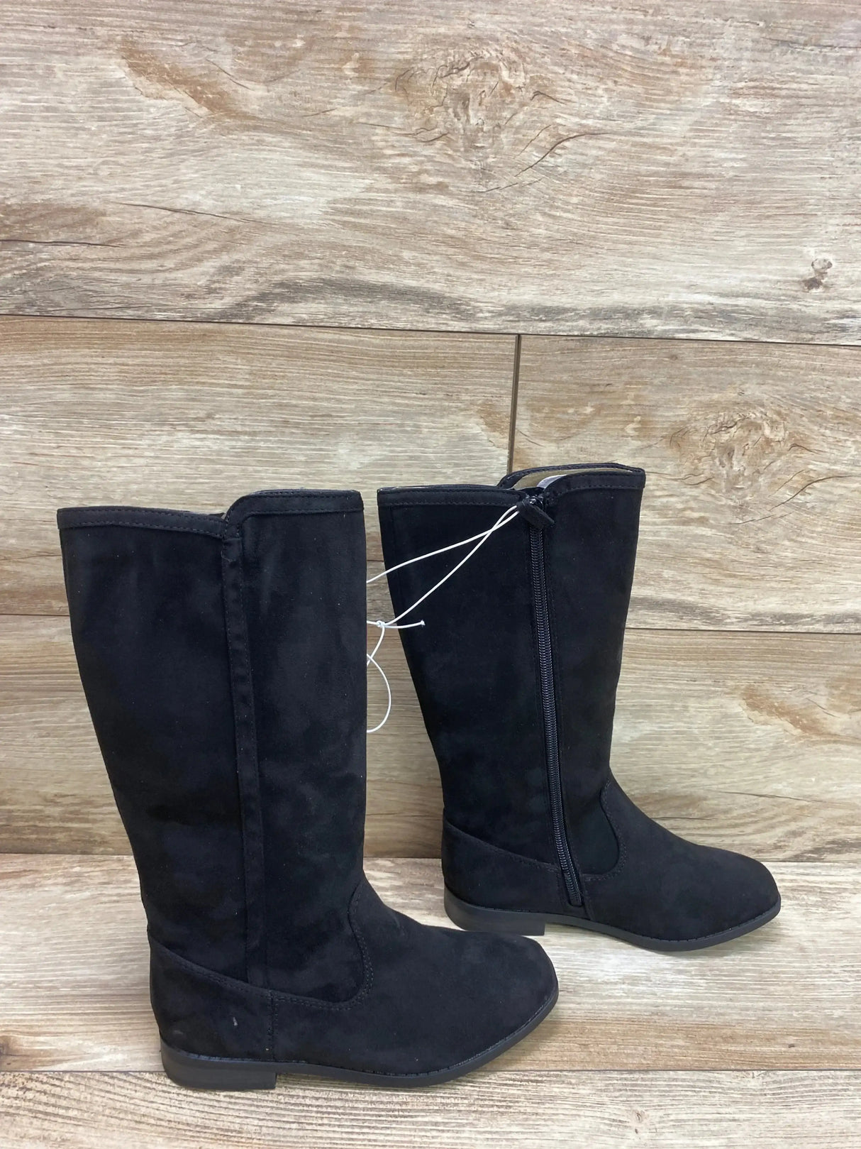 Side view of Cat & Jack Mylah tall black riding boots showcasing side zipper and low heel on wood floor background