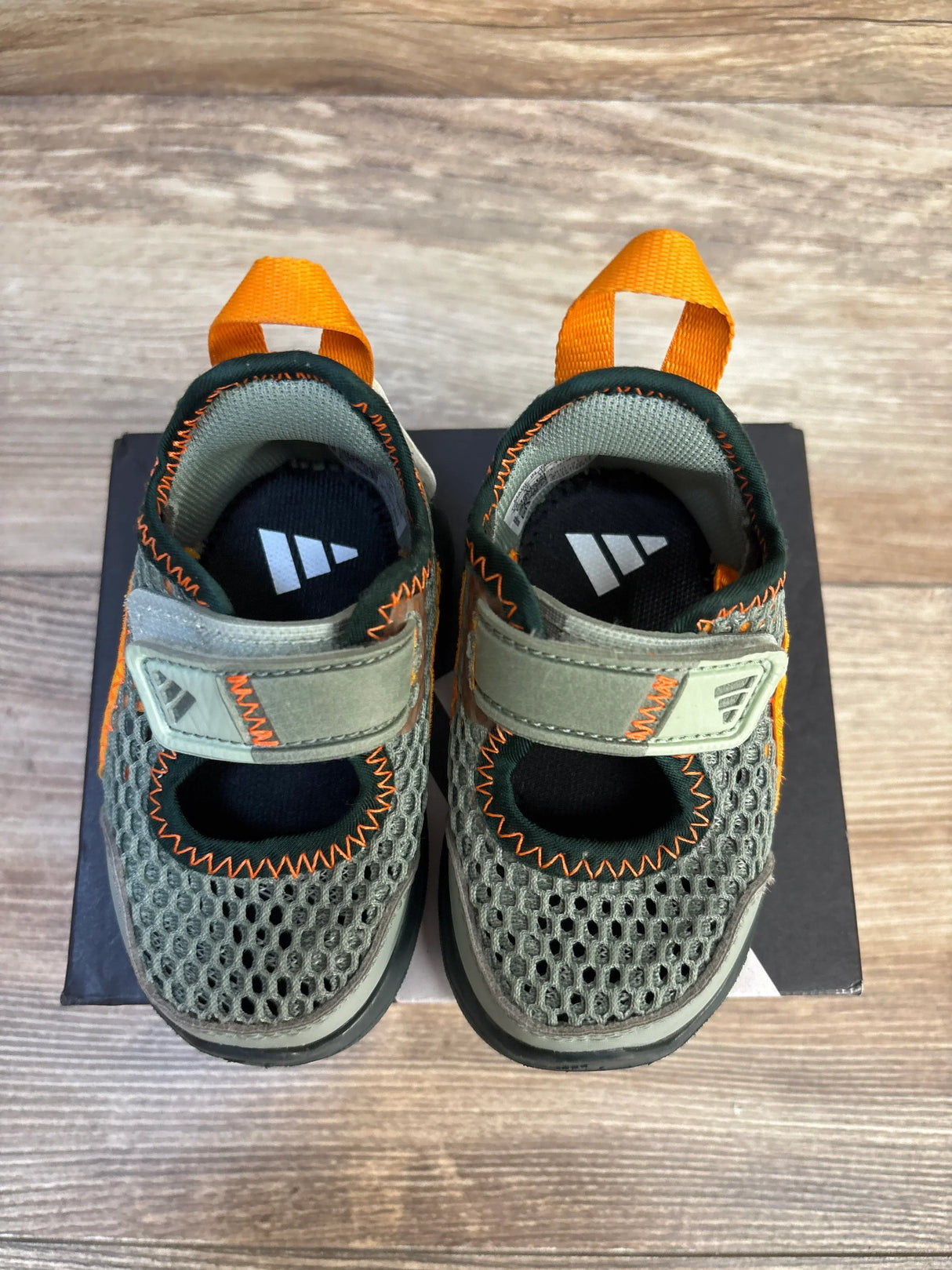 Kids gray mesh sandals with orange accents and velcro straps on a wooden surface