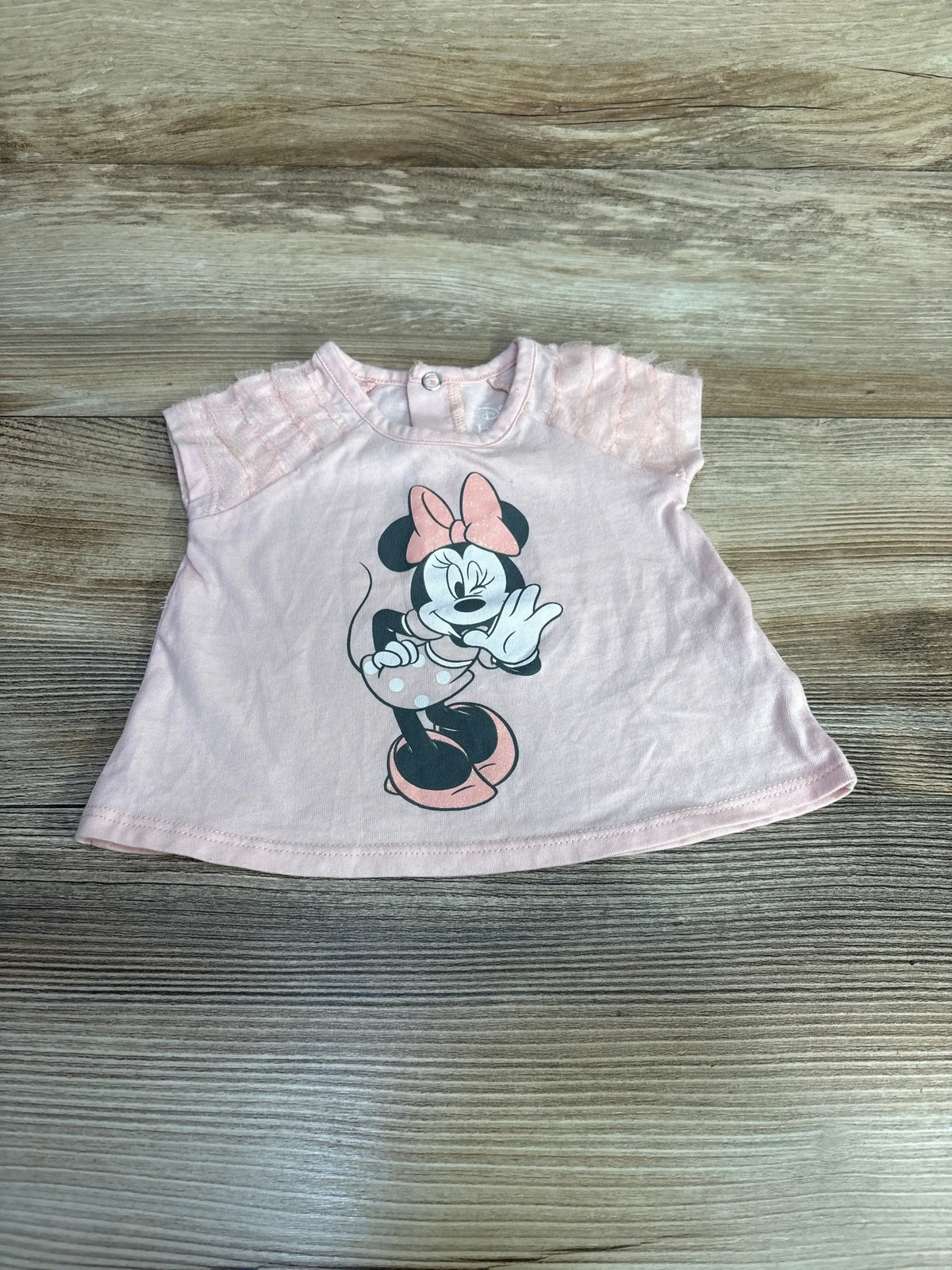 Top-down view of pink Disney Baby Minnie Mouse baby shirt (3-6 months) showcasing printed Minnie graphic and lace cap sleeves on light wood background