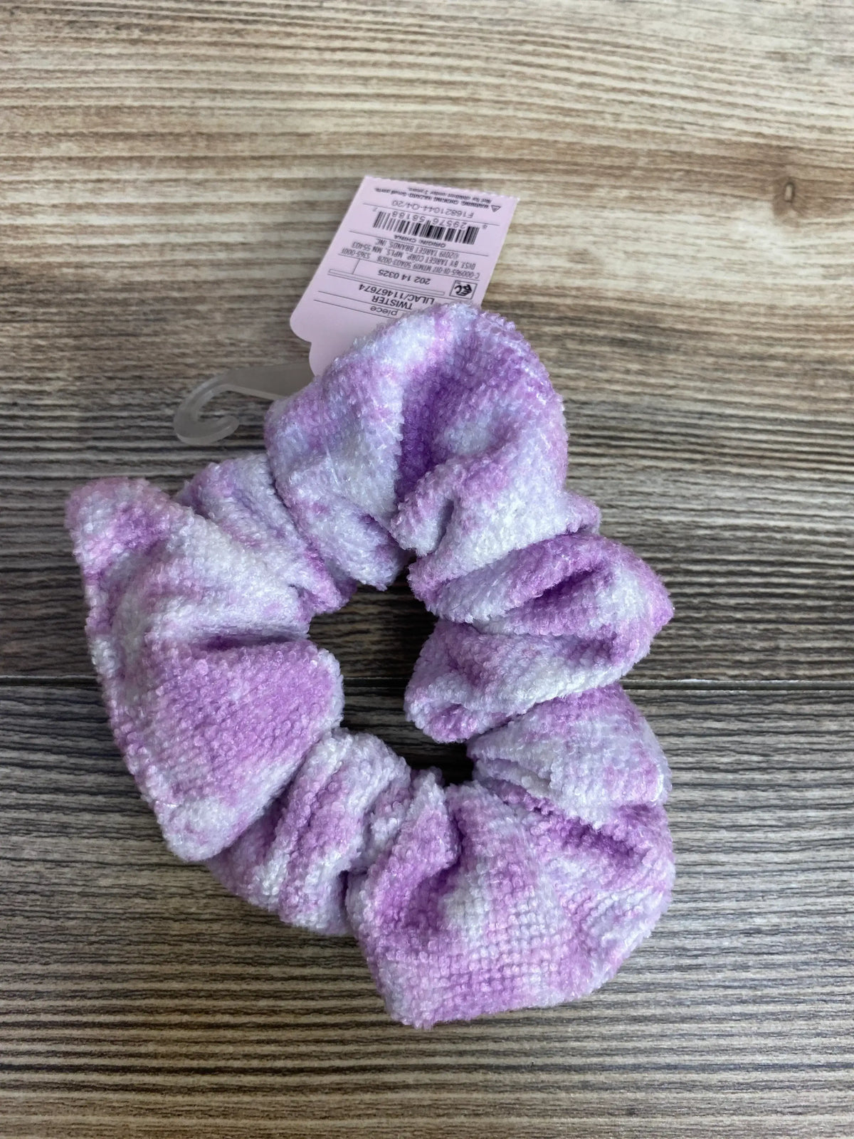 Soft purple and white tie-dye chenille hair scrunchie on wooden surface with product tag