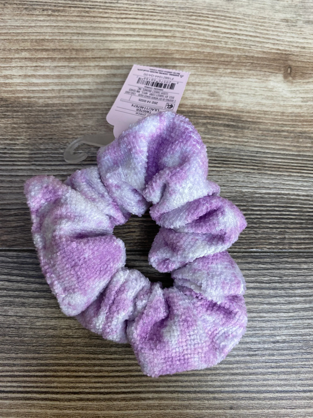 Soft purple and white tie-dye chenille hair scrunchie on wooden surface with product tag
