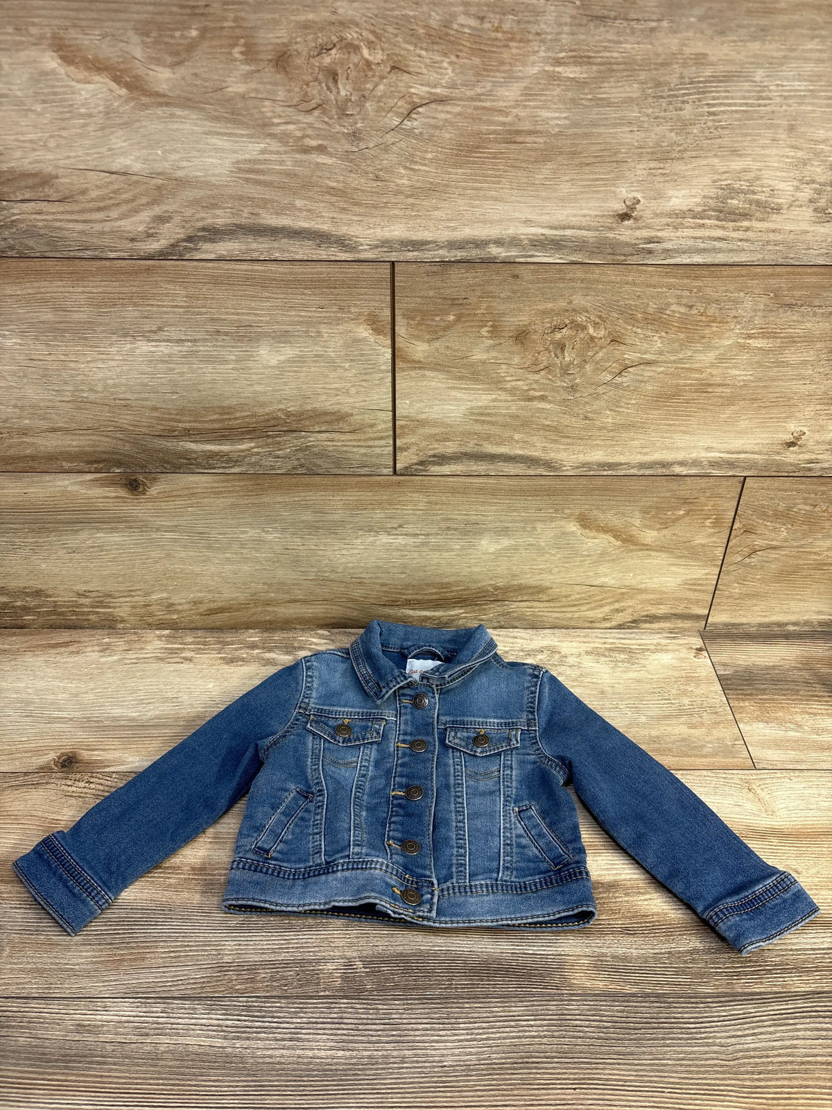 Blue Cat & Jack denim jacket for toddlers, size 18m, laid flat on a wooden background.