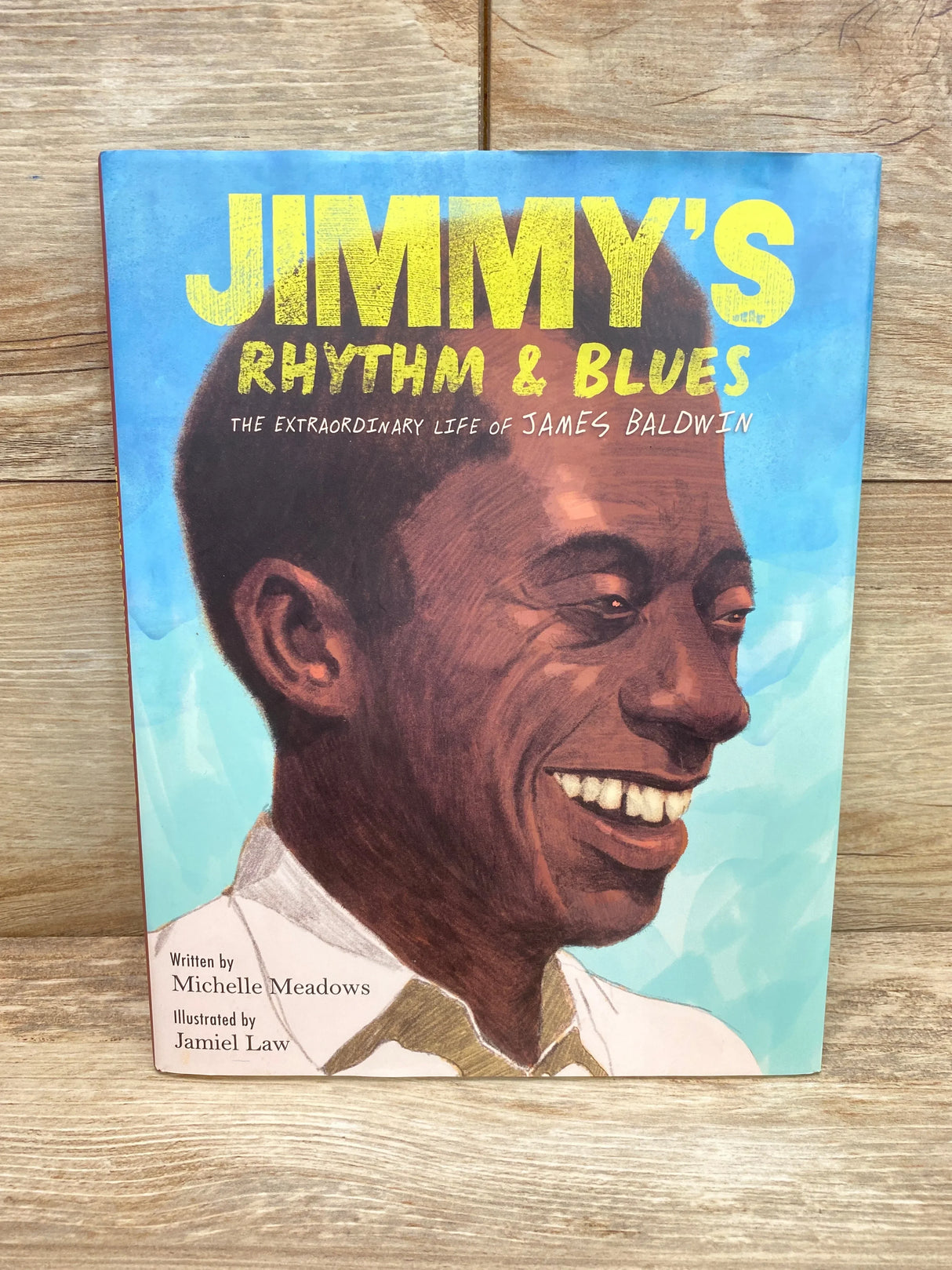 Front view of hardcover Jimmy's Rhythm and Blues with illustrated portrait of James Baldwin and bold yellow title on blue