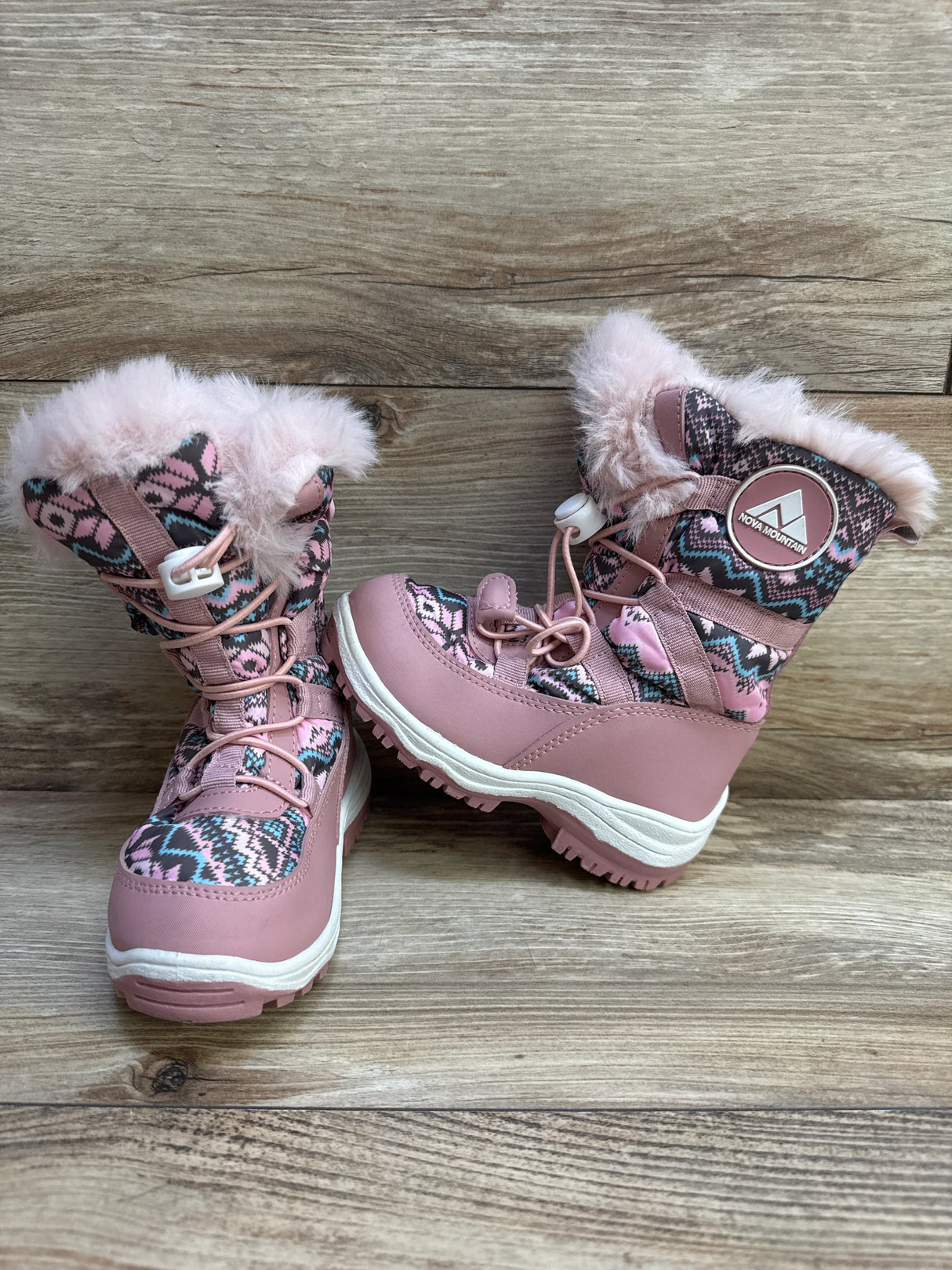 Front and side of Nova Mountain pink boots with faux-fur cuff, patterned shaft, lace toggle and lug sole on wood floor