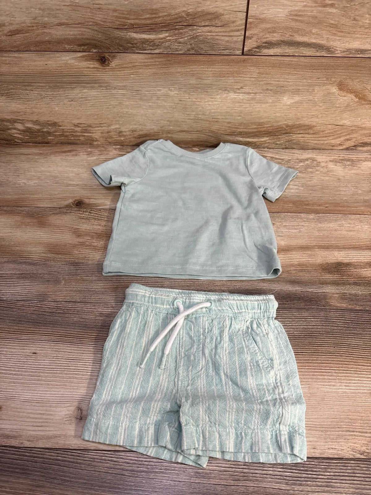 Flat lay of C&C California kids mint short-sleeve shirt and striped linen drawstring shorts showing elastic drawstring waist on wood background
