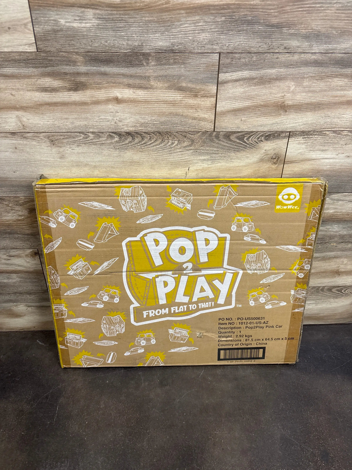 Front view of Pop2Play pink cardboard car packaging showing flat-pack design and dimensions 81.5 cm x 64.5 cm x 5 cm