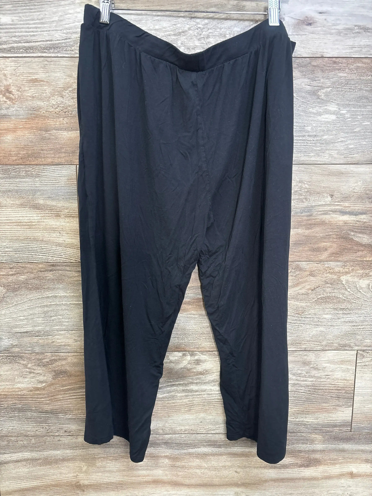 Front view of Kindred Bravely black wide-leg maternity lounge pants showing V-shaped elastic waistband, hanging against wood background