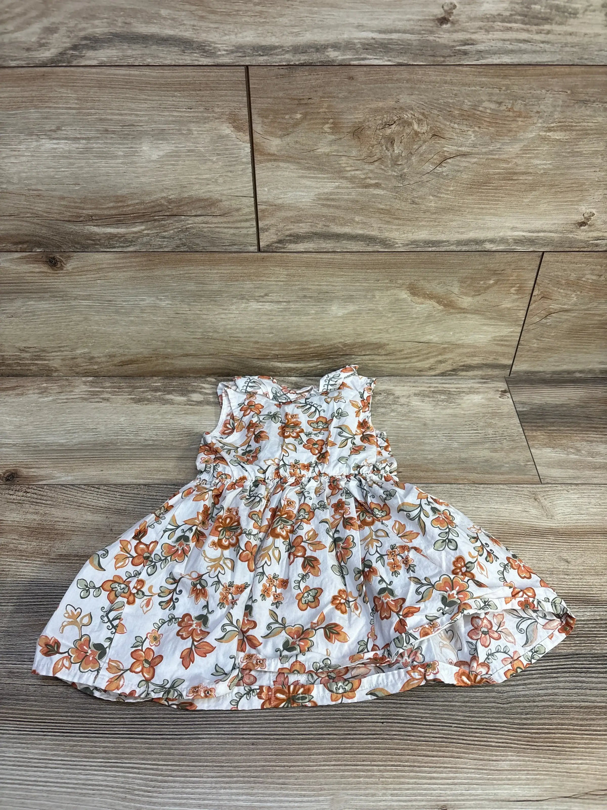 Front view of white Little Lass button front floral dress, size 12m, sleeveless 100 percent cotton on wood flooring
