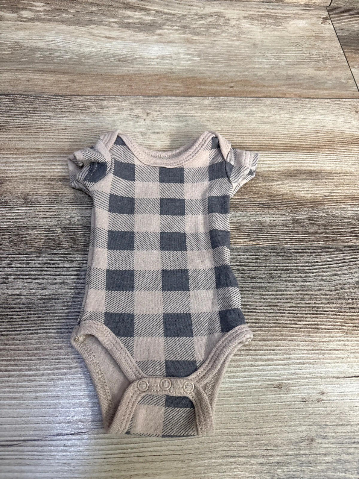 Front view of Hudson Baby tan preemie bodysuit showcasing a plaid pattern and three-snap bottom on a wood-grain background