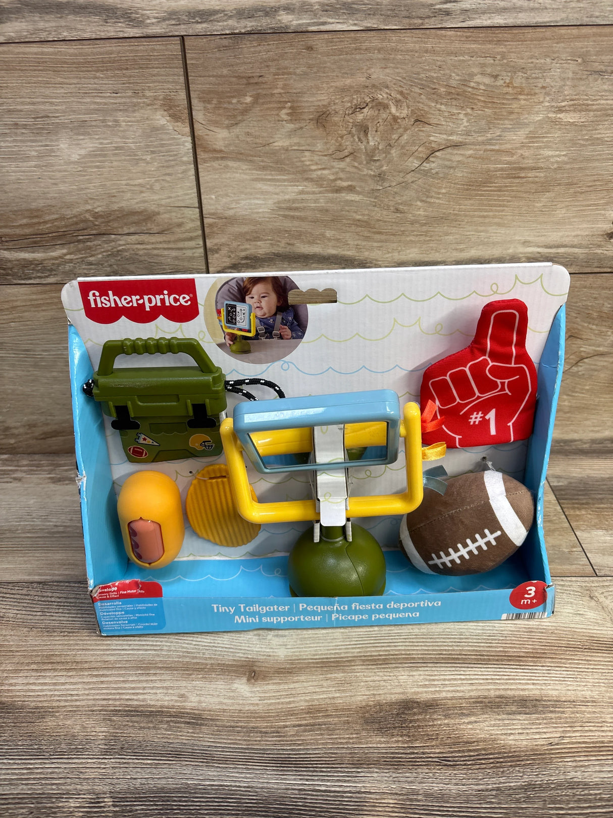 Front view of Fisher-Price Tiny Tailgater playset showing foam football, red foam finger number 1, and yellow goalpost in box
