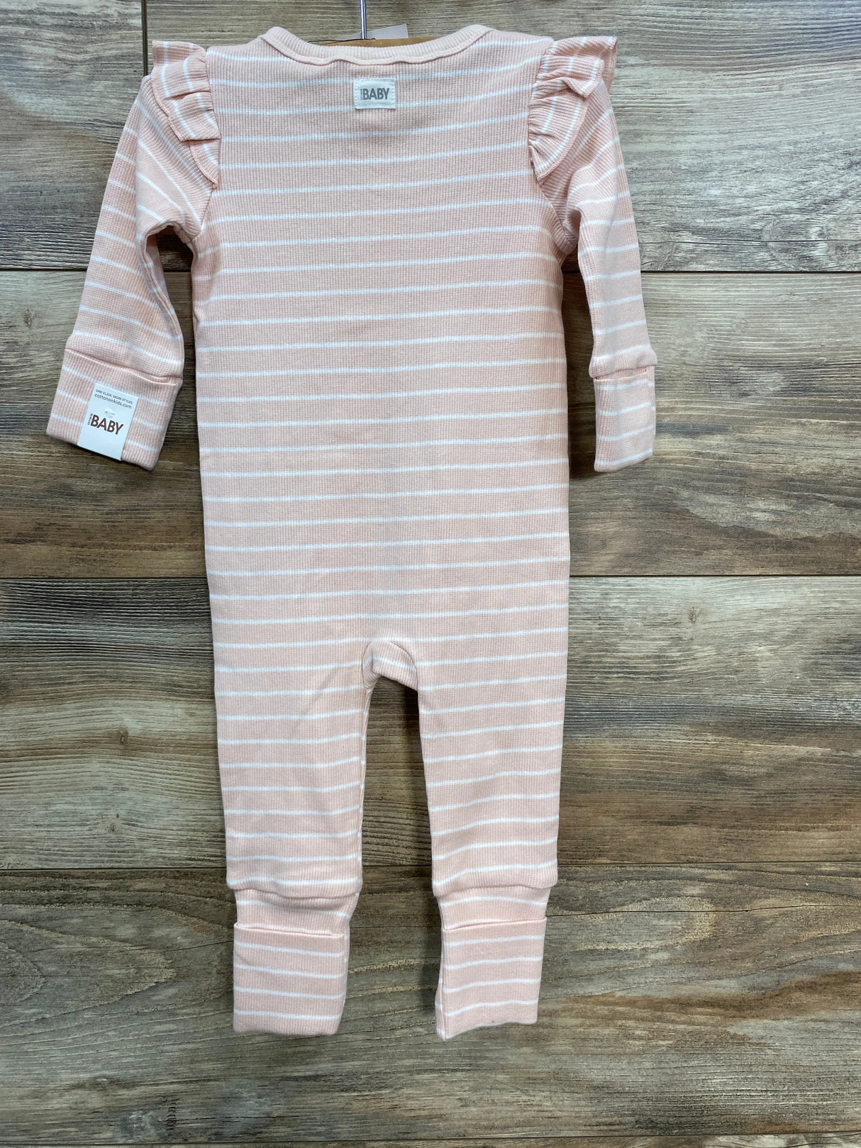 Pink and white striped baby romper with ruffle shoulders on wooden background