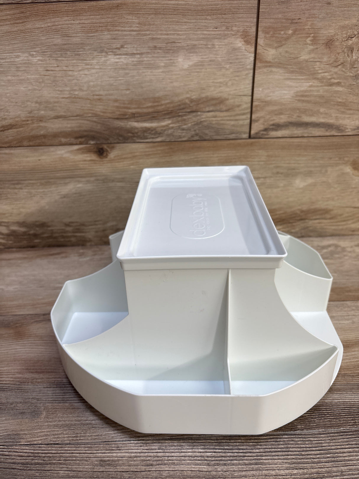 Front view of Dexbaby The Spin changing station, white, round divided storage compartments and removable top on wood