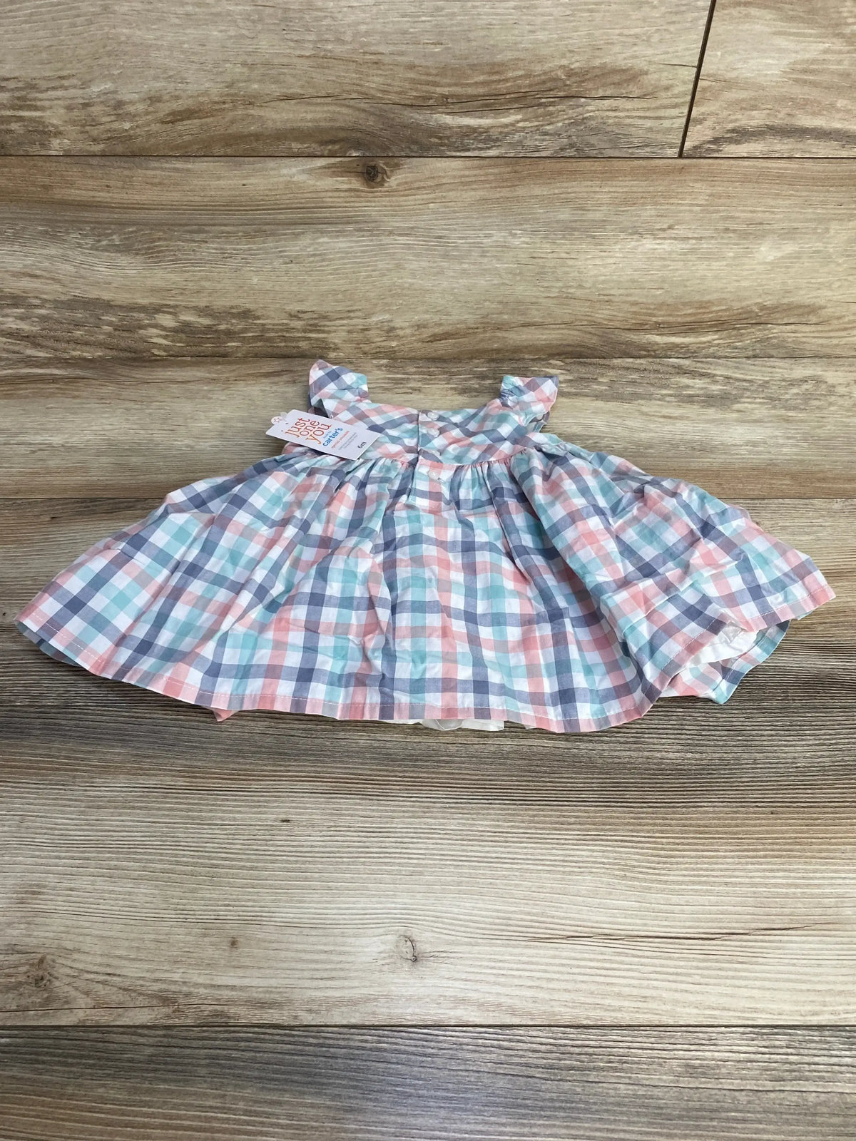 Flat lay of NEW Just One You two piece plaid dress and bloomers sz 6m showcasing pink teal and navy gingham flutter sleeve dress with hangtag on wood plank floor