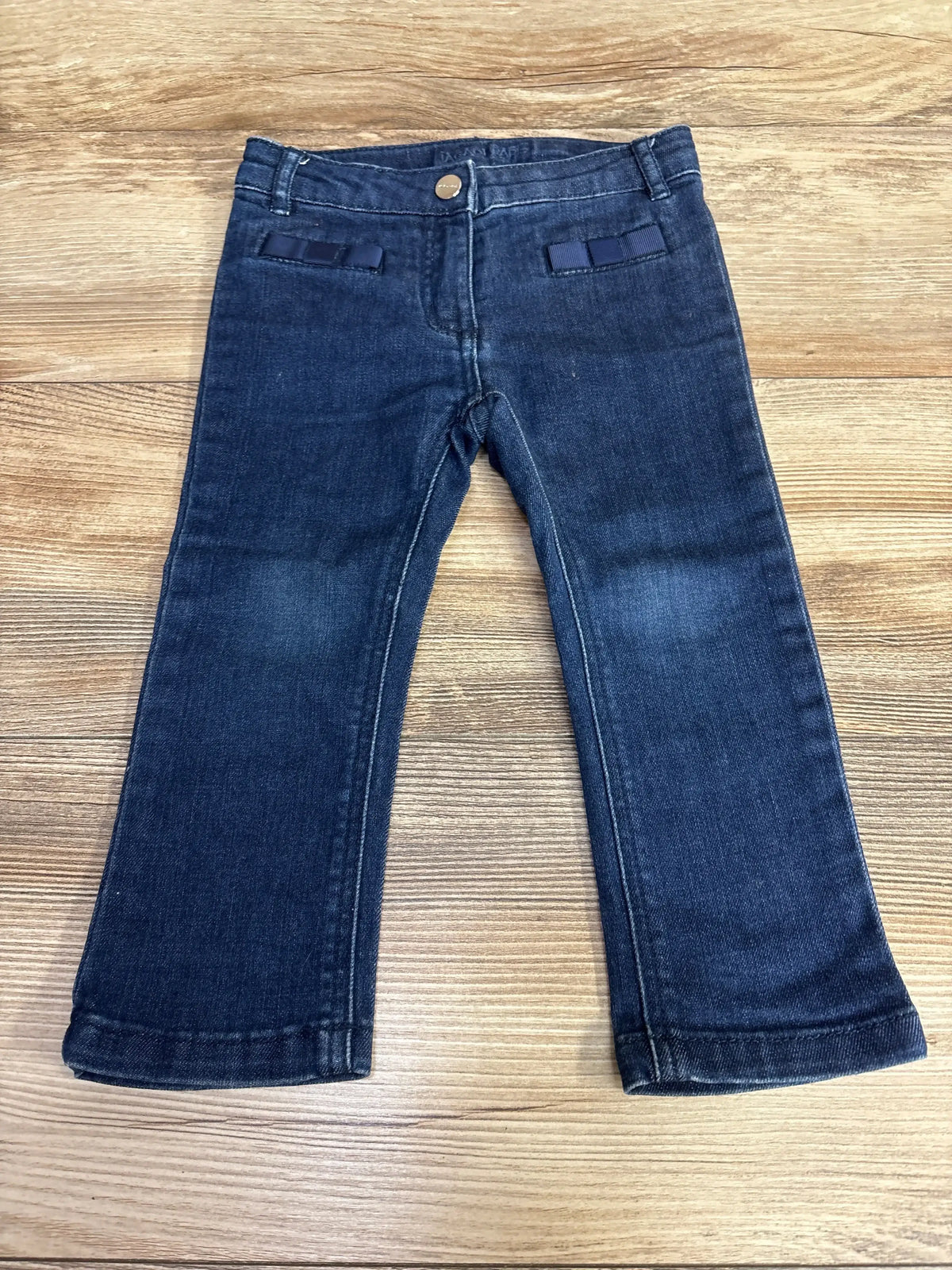 Dark wash toddler jeans with straight legs on wood background, gently used kids clothing