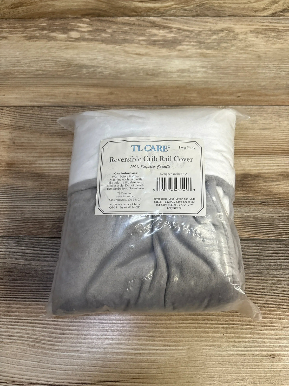 Front view of NEW TL Care Heavenly Soft Chenille Reversible Crib Rail Cover 2pk showcasing grey and white chenille covers in sealed plastic packaging on wood plank floor