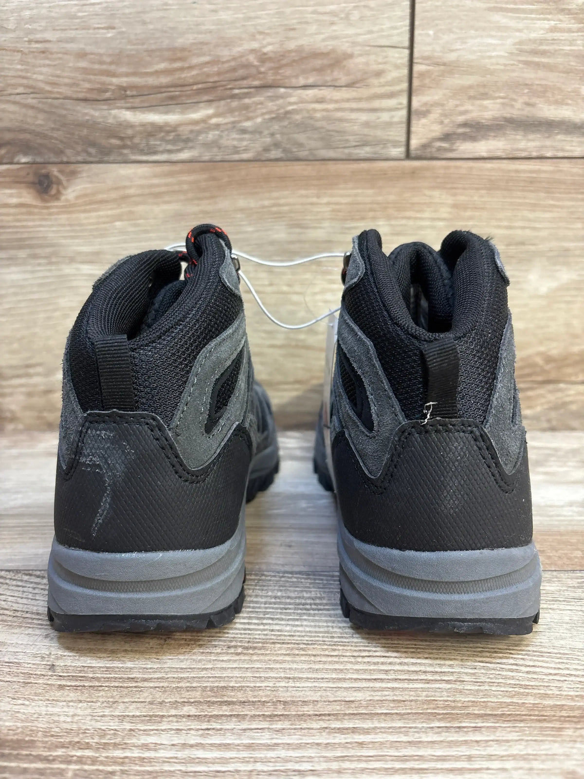 Rear view of Cat and Jack Patsy hiking boots in black and gray with padded collars and lugged soles on a wood floor