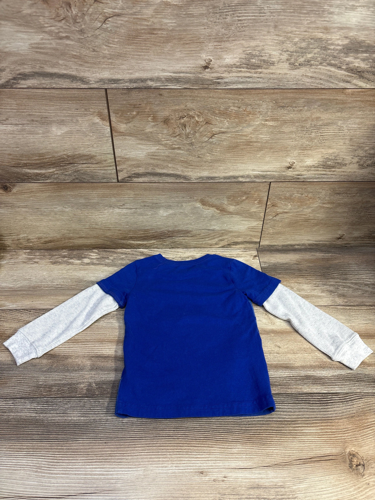 Back view of Carter’s layered-sleeve toddler shirt size 2T showing blue body with heather gray long sleeves on wood background