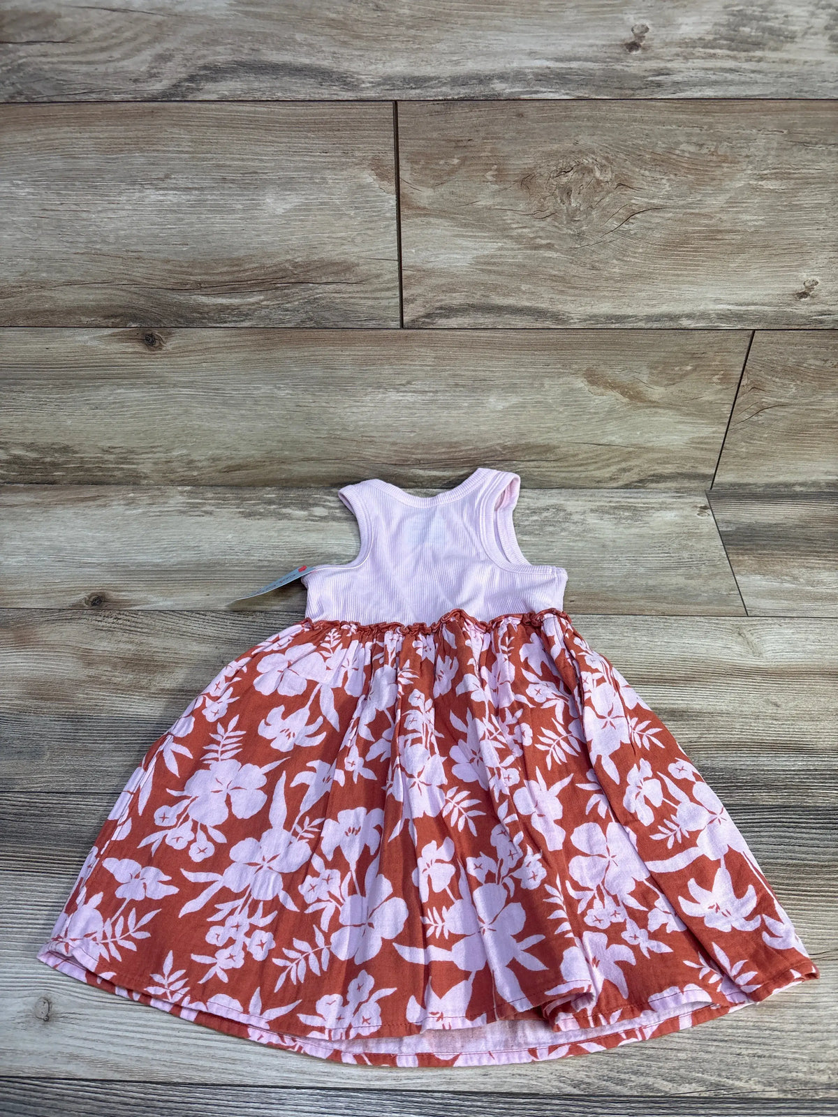 Cat & Jack ribbed light pink tank dress with a rust-colored floral skirt on a wood background