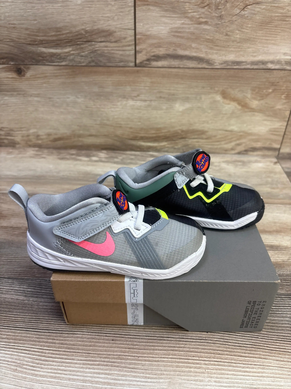 Side view of Space Jam x LeBron 18 Low TD sneakers with gray, black, pink, and neon accents on a shoebox
