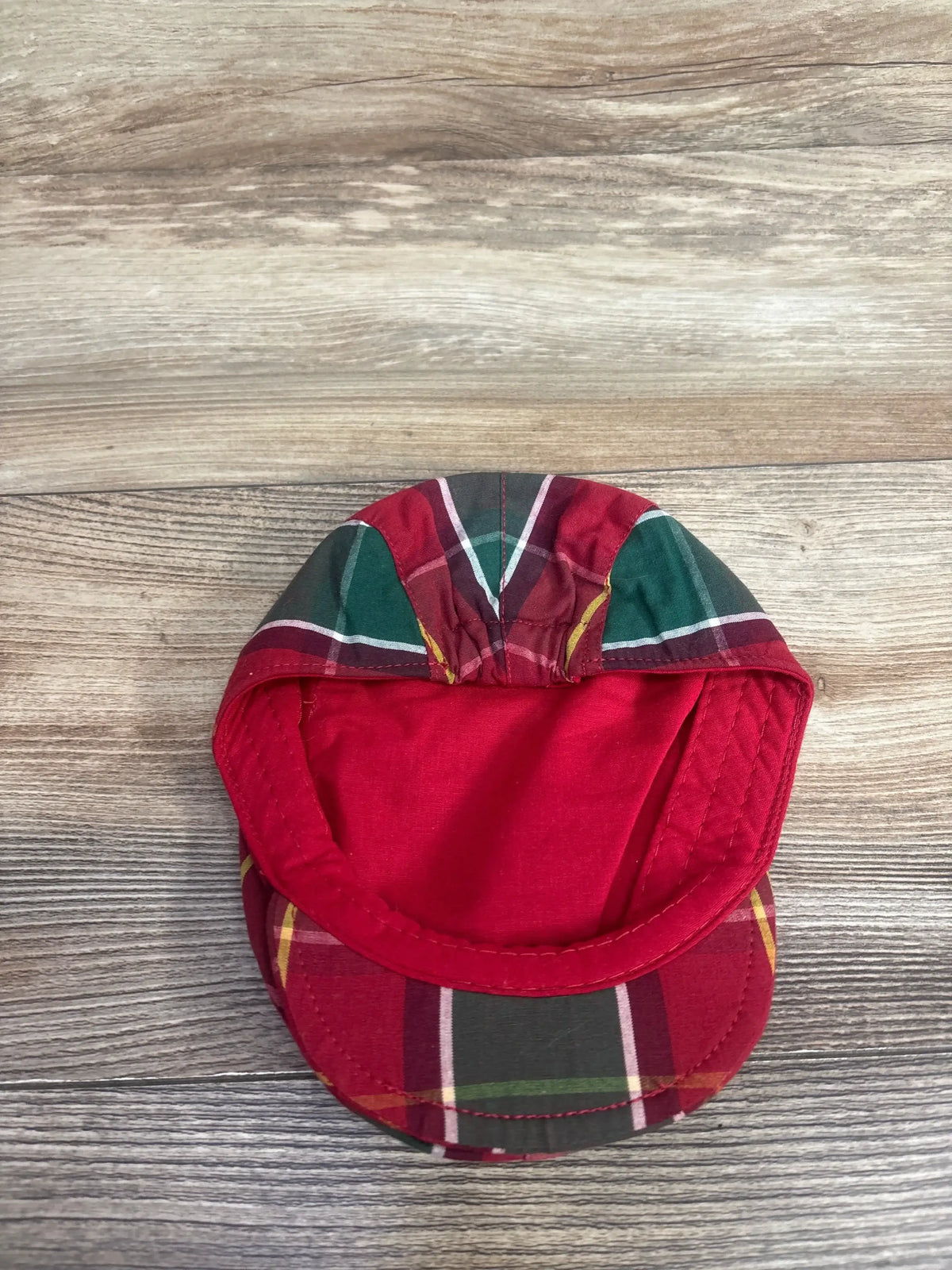 Red and green plaid baby hat for kids, festive holiday clothing accessory on wood background