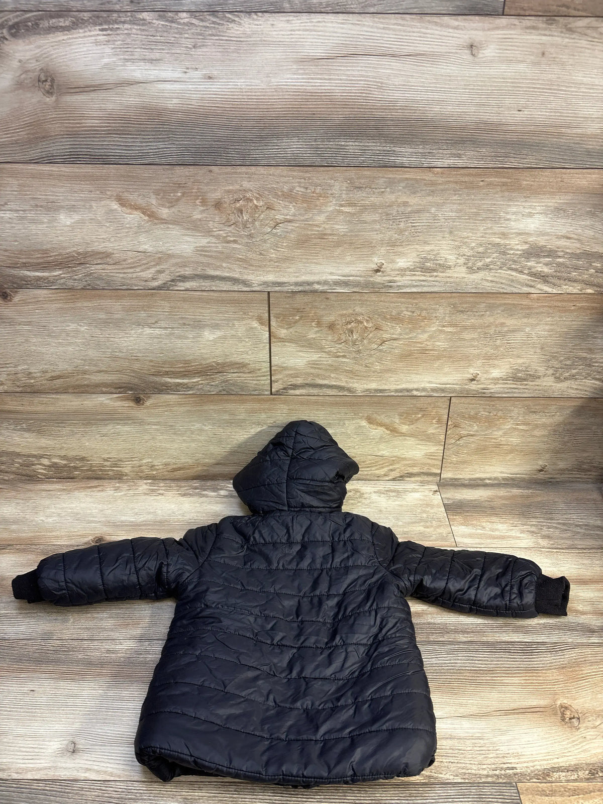 Back view of a Shein black fur lined puffer jacket for kids size 4T on a wood background