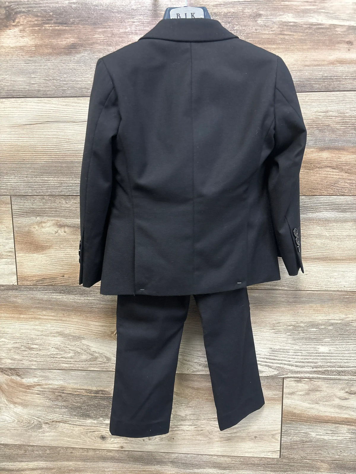 Back view of Boltini black 4-piece suit set showcasing slim-fit blazer and matching pants on a wood floor