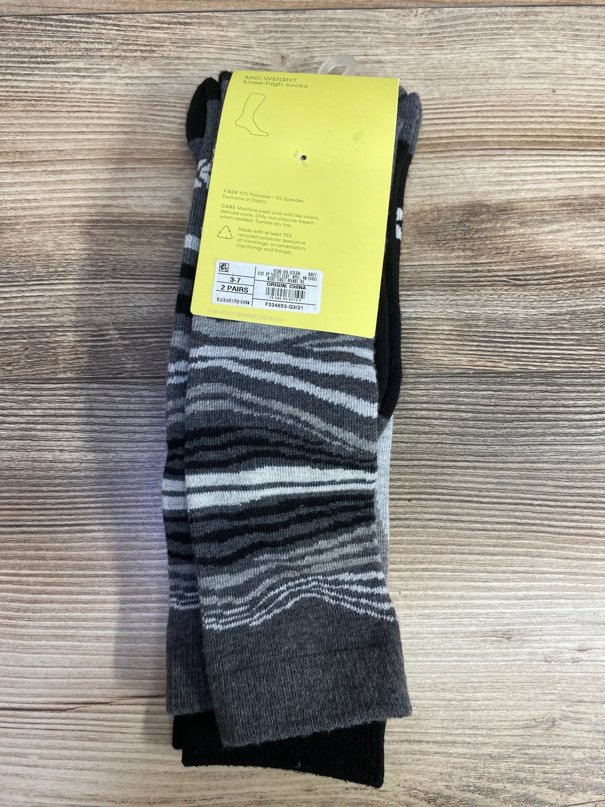 Two pairs of mid-weight knee-high socks with black and gray zebra stripes on wood background