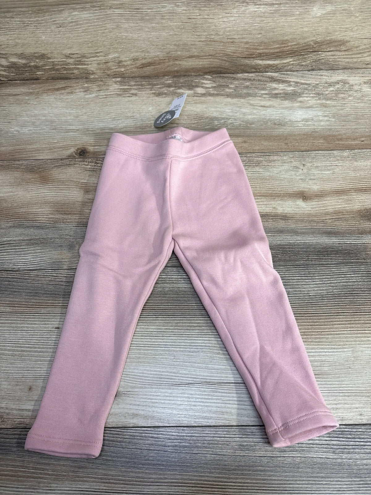 Pink baby leggings with tag on wood surface, children's resale clothing