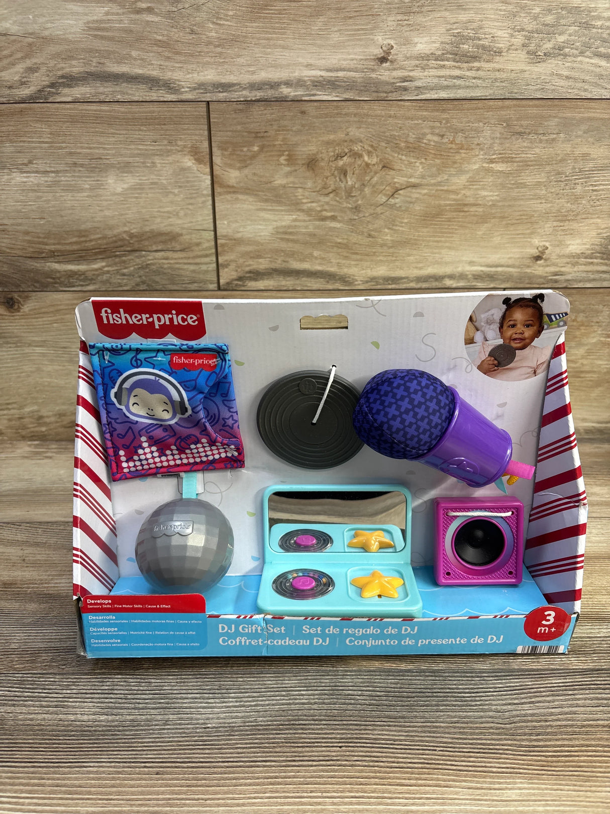 Front view of Fisher-Price Mini Me Moments DJ gift set showcasing purple microphone, toy turntables, disco ball and speaker in box on wood background