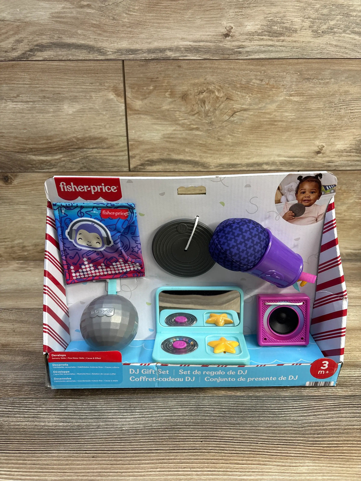 Front view of Fisher-Price Mini Me Moments DJ gift set showcasing purple microphone, toy turntables, disco ball and speaker in box on wood background