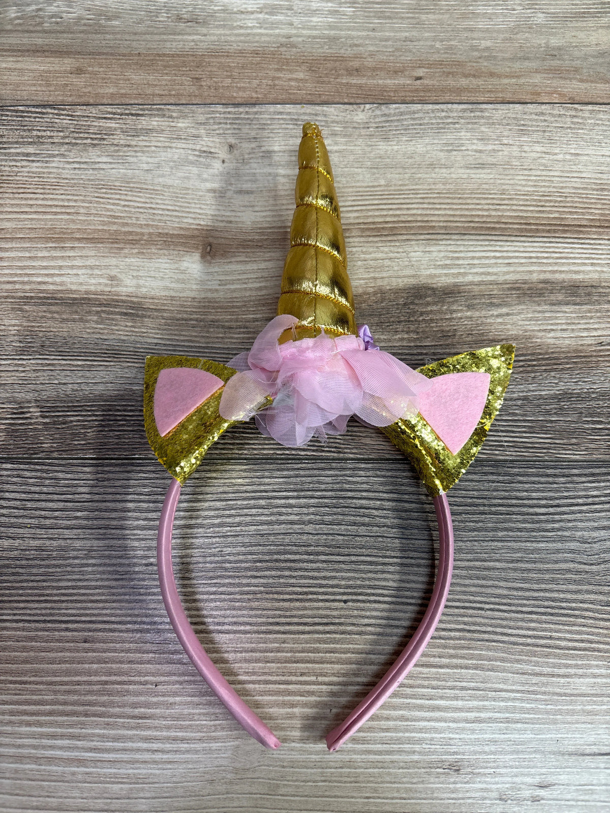 Front view of BookMyCostume Unicorn Horn Headband showcasing a gold horn, glitter ears, pink flowers, and pink band