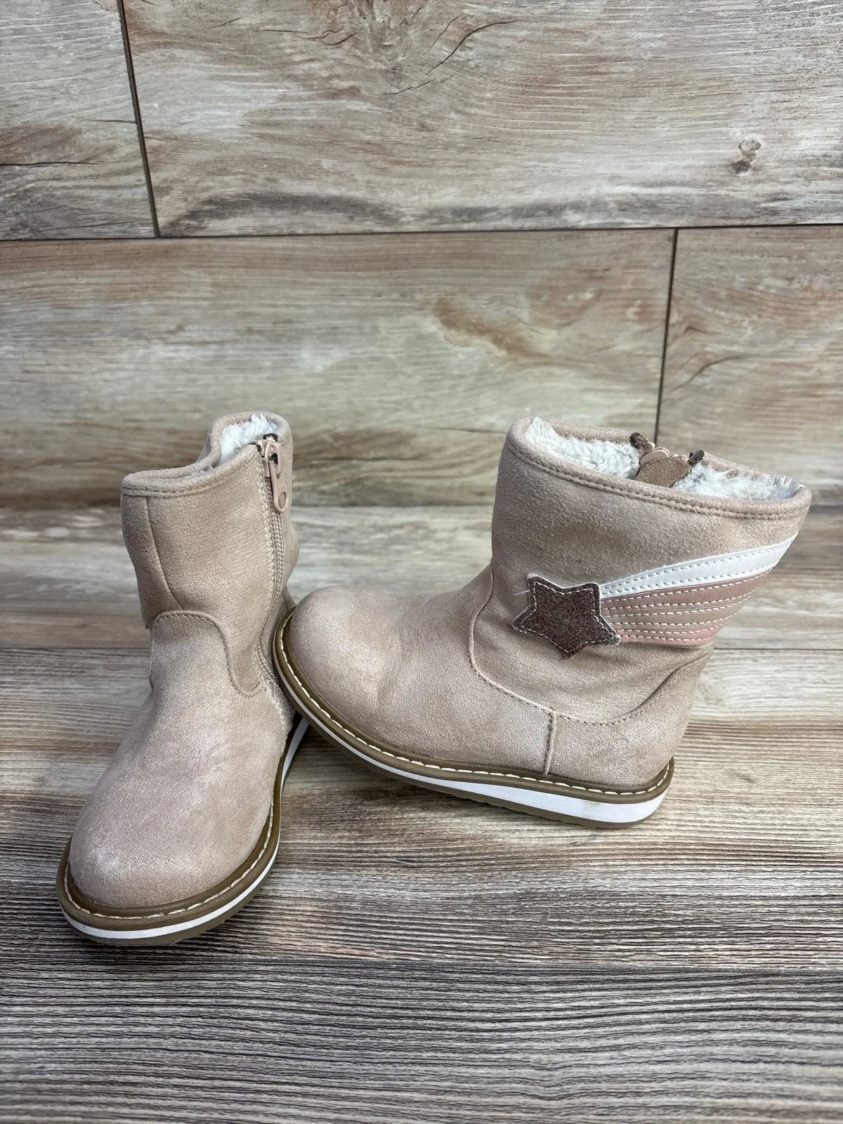 Pink toddler boots with star patch and faux fur lining on wood background