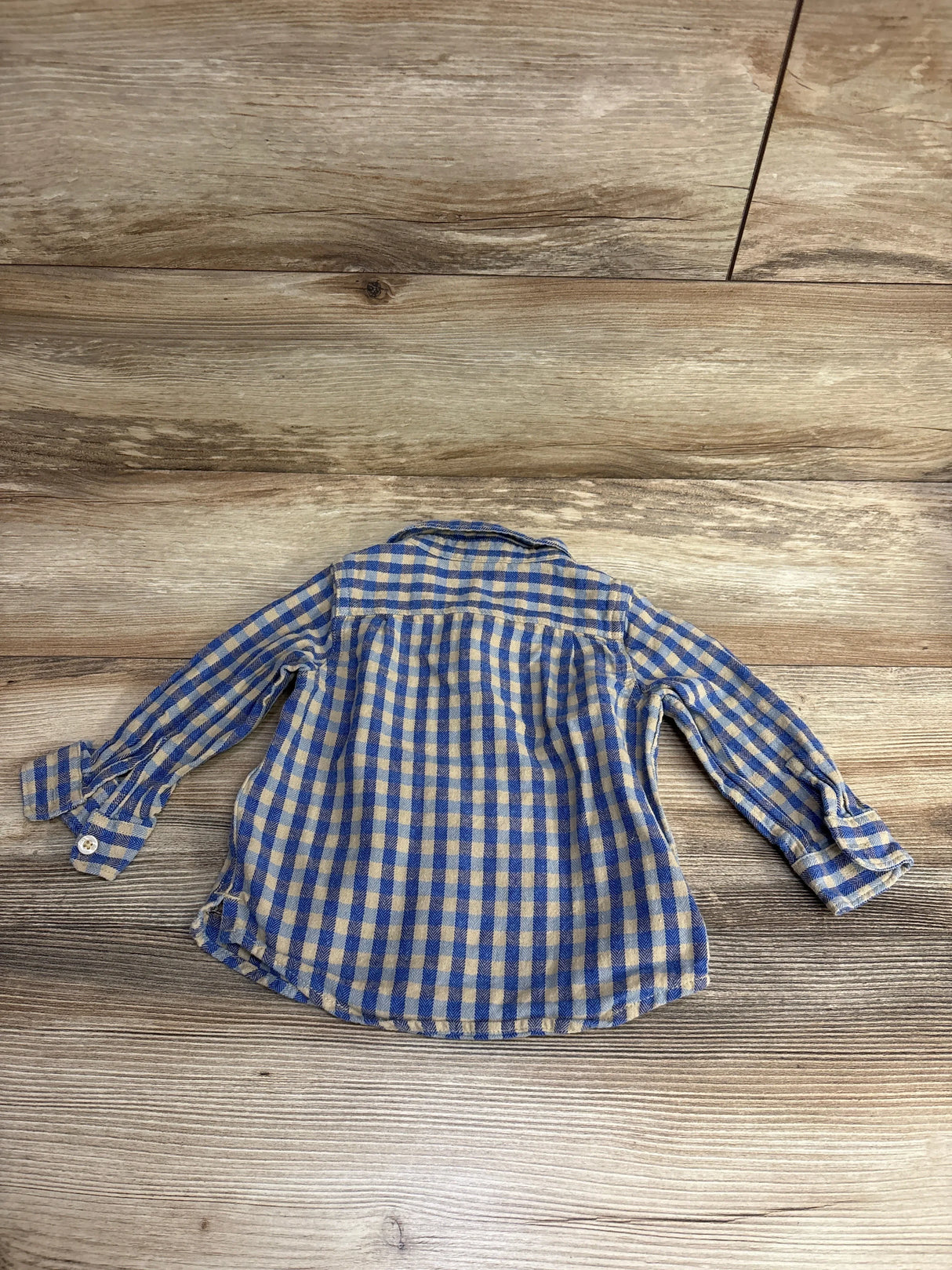 Back view of toddler's blue and tan checkered long-sleeve shirt on wood floor