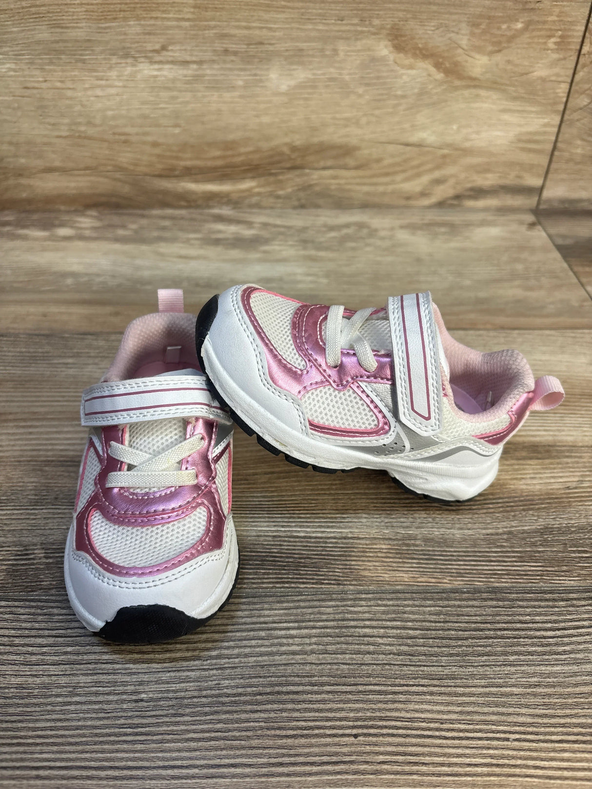 Pink and white toddler sneakers with Velcro straps on wood background