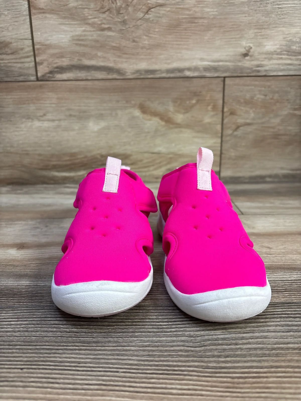 Front view of Cat & Jack Speedo water shoes in pink, size 12C, showcasing white soles and heel pull tabs on a wood floor