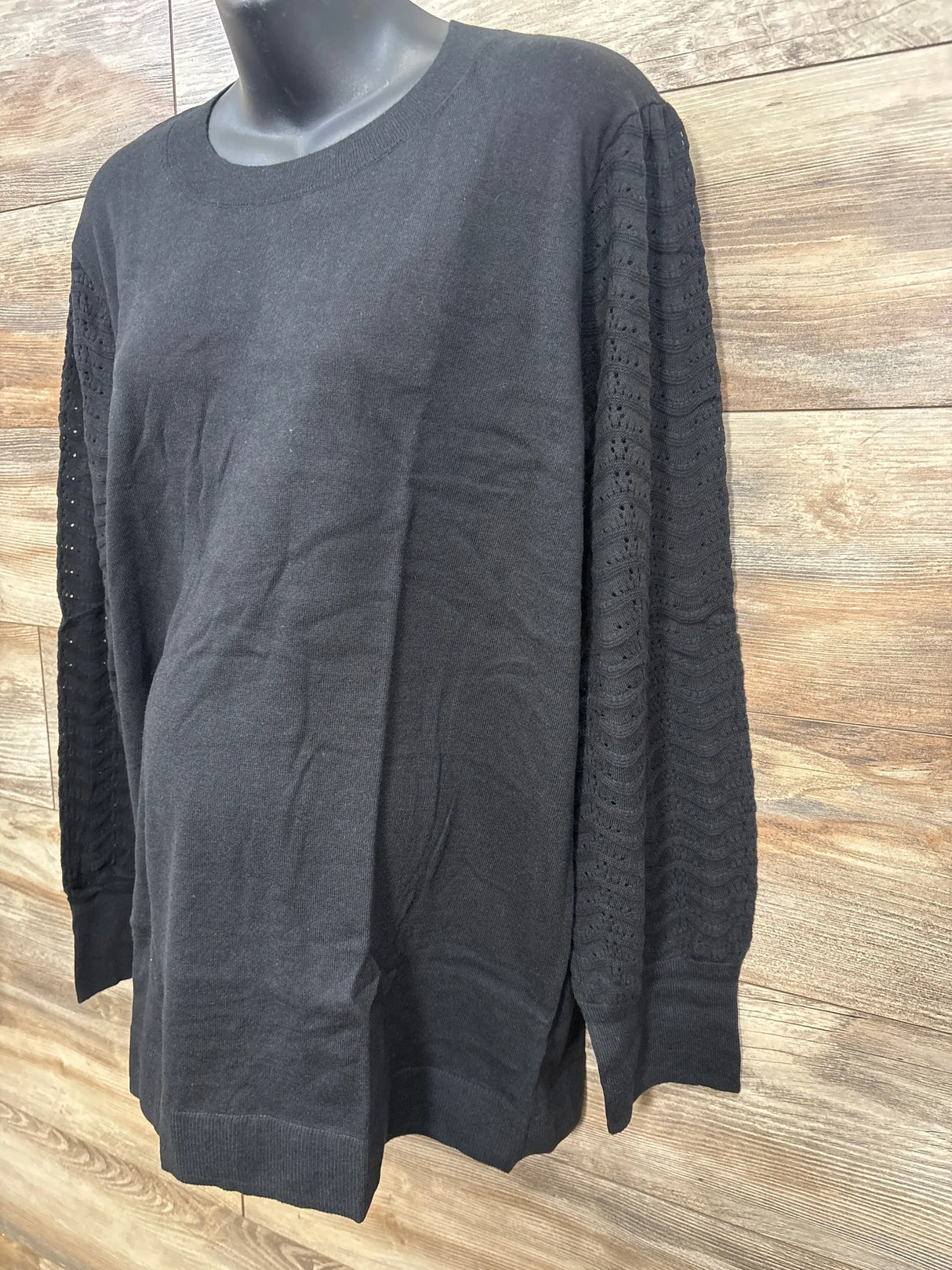 Black maternity sweater with textured lace sleeves on mannequin against wood background