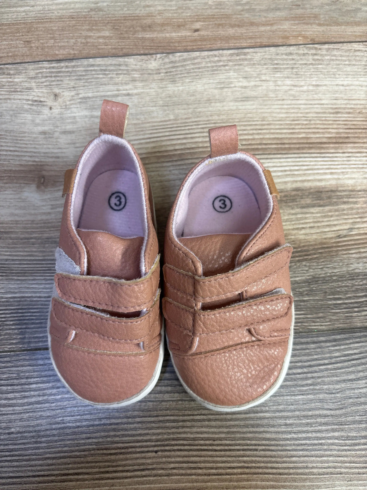 Top view of Rokment pink non-slip crib shoes, size 3C, with double hook and loop straps and pull tabs on wood grain