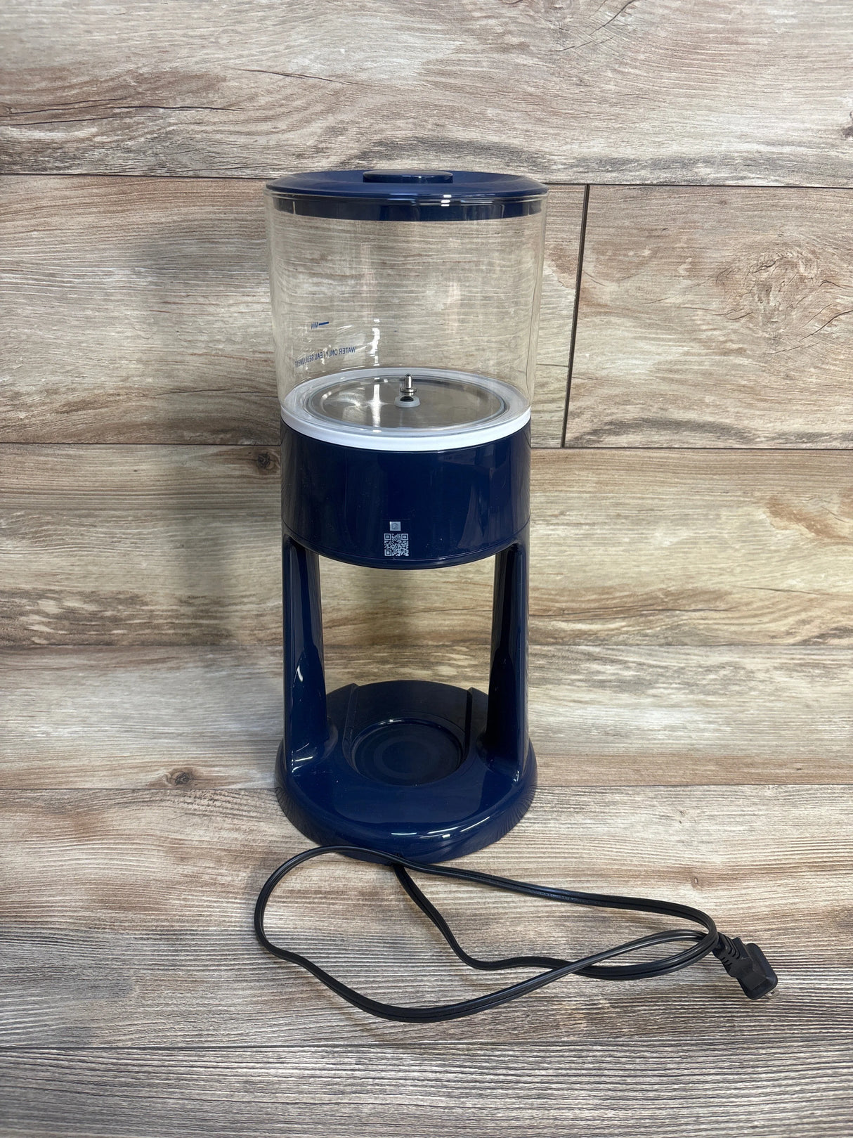 Electric baby bottle sterilizer with clear chamber and navy base on wood background