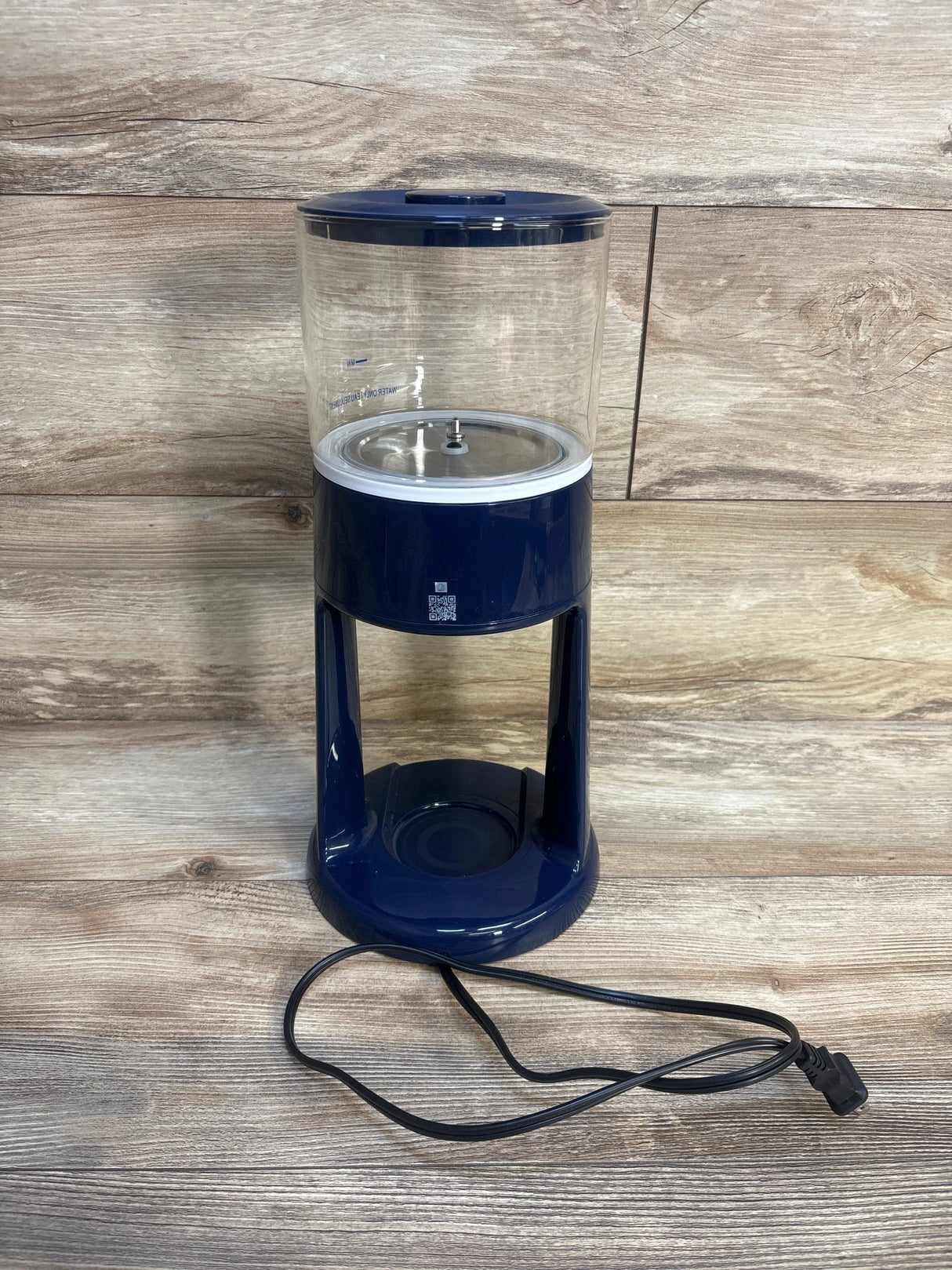 Electric baby bottle sterilizer with clear chamber and navy base on wood background